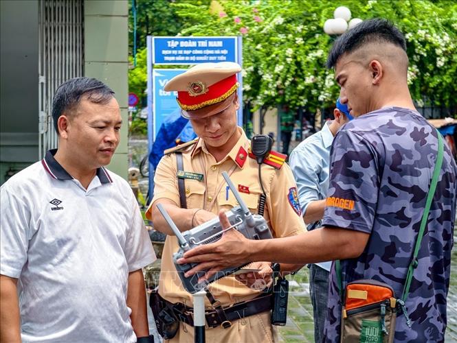 Cán bộ đội Cảnh sát giao thông số 7, Phòng Cảnh sát giao thông Hà Nội, mời người vi phạm xem lại hình ảnh từ thiết bị điều khiển UAV, đảm bảo tính chính xác, khách quan, minh bạch. (Ảnh: Trung Nguyên/TTXVN)